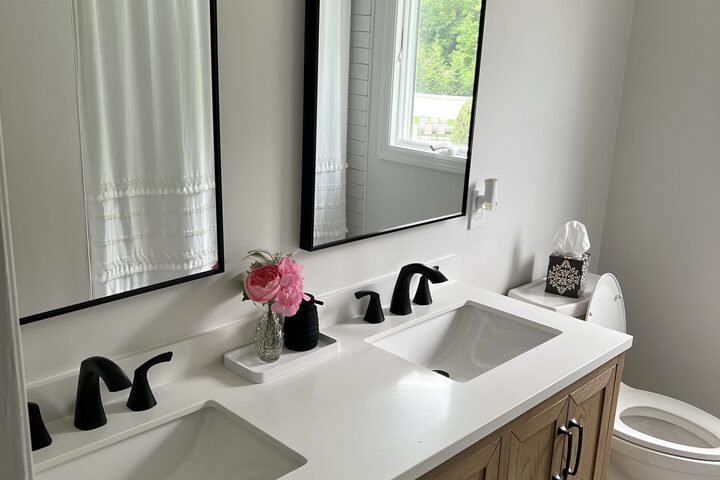 Finished bathroom with a double vanity, quartz counter and matte black faucets.